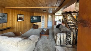 A wooden interior with a sofa, a coffee table, and a TV mounted on the wall. - Mountain Chalet next to Angeles National Forrest and near Hard Rock Casino Tejon (Frazier Park)