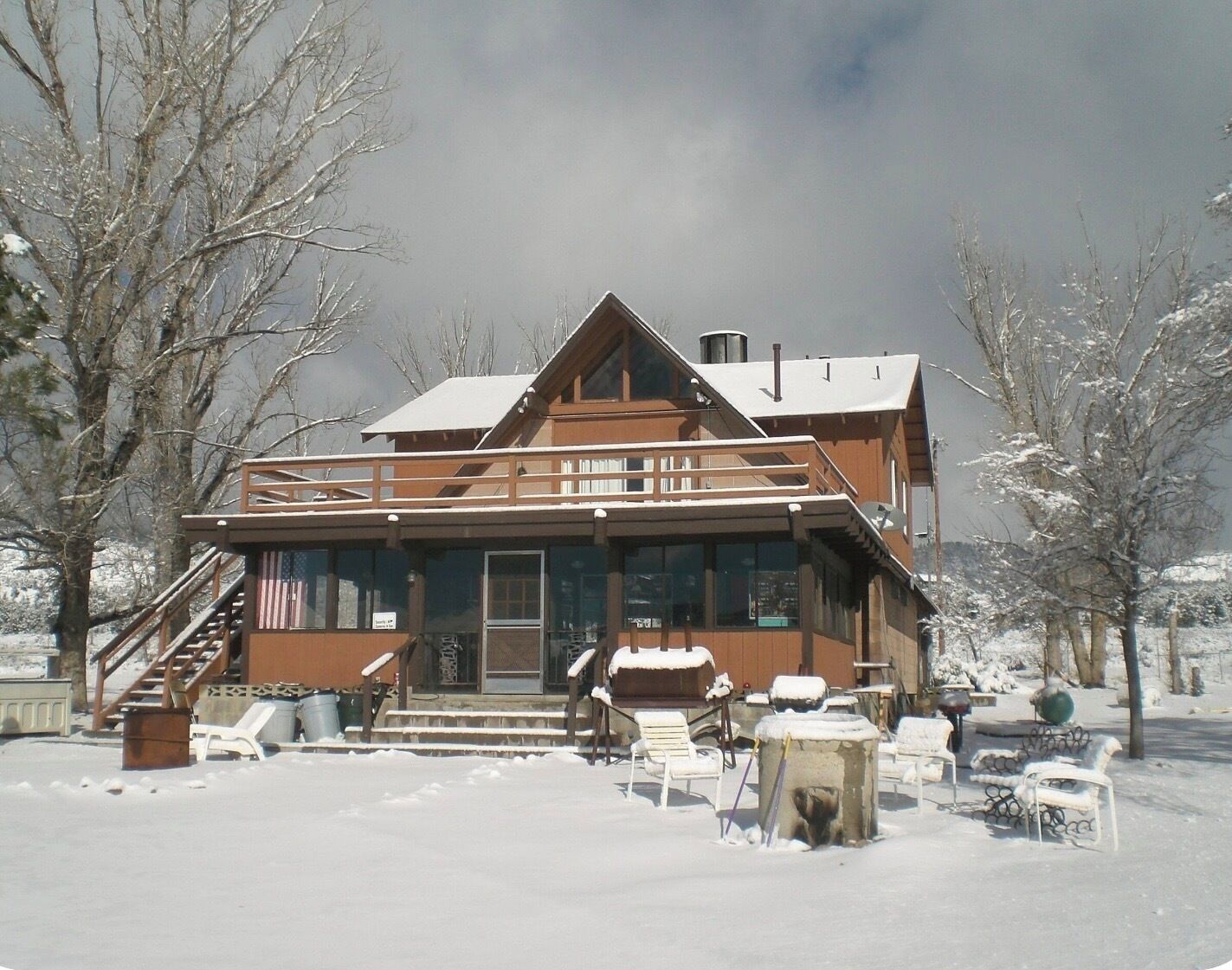 Un lodge su due piani con un balcone, un portico coperto e un paesaggio innevato.