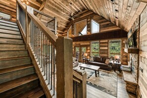 A wooden interior with a staircase, a living area with a fireplace, and large windows. - 5BR w/Indoor Pool*Theater*Game Room*Hot Tub*Views (Pigeon Forge)