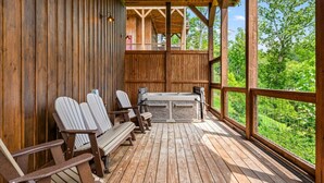 Puinen terassi, jossa on Adirondack-tyyliset puutarhatuolit ja poreallas, ja josta avautuu näkymä vehreään maisemaan.