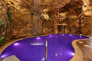 A spa pool with a rocky interior, a waterfall feature, and a clear blue pool. - 5BR w/Indoor Pool*Theater*Game Room*Hot Tub*Views (Pigeon Forge)
