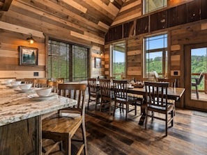 A rustic wooden interior with a dining area, wooden chairs, and a marble countertop. - 5BR w/Indoor Pool*Theater*Game Room*Hot Tub*Views (Pigeon Forge)