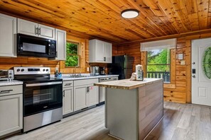 A modern kitchen with wooden paneling, stainless steel appliances, and a large island. - 5 Min to Pigeon Forge! 5BR*Hot Tub*Fire Pit*Quiet (Pigeon Forge)