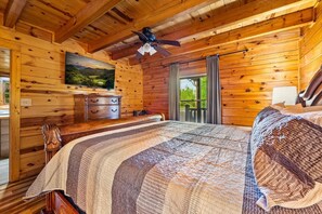 A wooden cabin bedroom with a bed, a dresser, a ceiling fan, and a painting on the wall. - 5 Min to Pigeon Forge! 5BR*Hot Tub*Fire Pit*Quiet (Pigeon Forge)