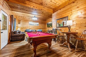A wooden interior with a pool table, a sofa, and a dining table. - 5 Min to Pigeon Forge! 5BR*Hot Tub*Fire Pit*Quiet (Pigeon Forge)