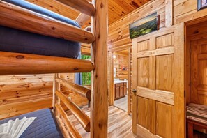 Ein Interieur einer Holzhütte mit Etagenbetten, einer Holztür und Blick ins Freie.