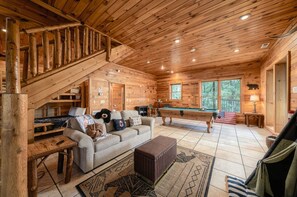 A wooden cabin interior with a pool table, sofa, and staircase. - Stunning MTN Views! Hot Tub*Pool Table*Privacy! (Gatlinburg)