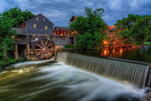 Eine Wassermühle mit einem großen Wasserrad, Holzhäusern und einem Teich.