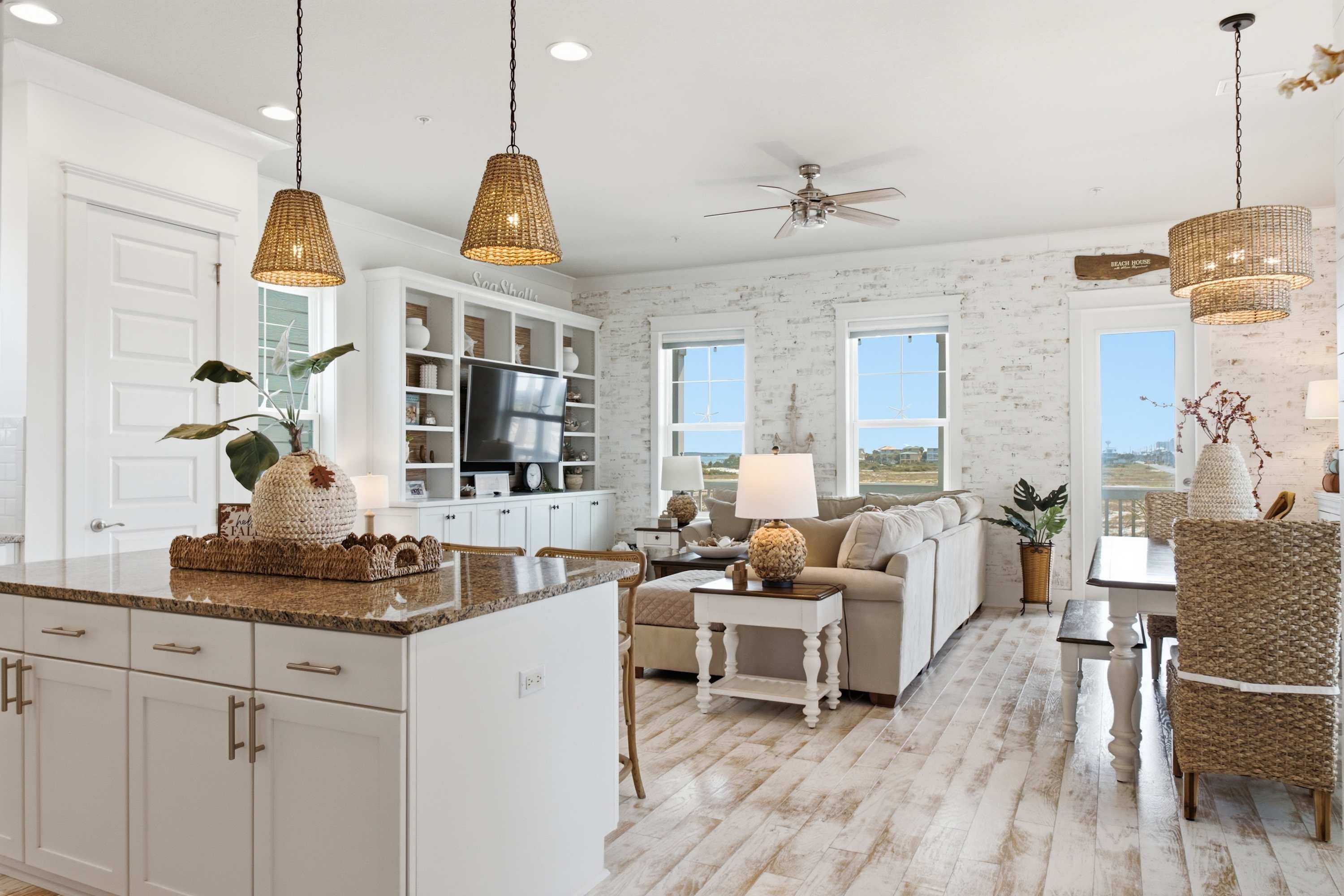 A spacious kitchen with white cabinetry, a central island, and a dining area with wicker chairs.