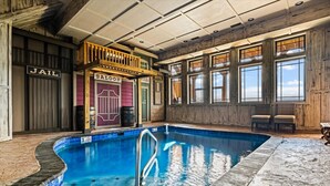 En indendørs pool med træterrasse og udsigt til himlen gennem store vinduer.