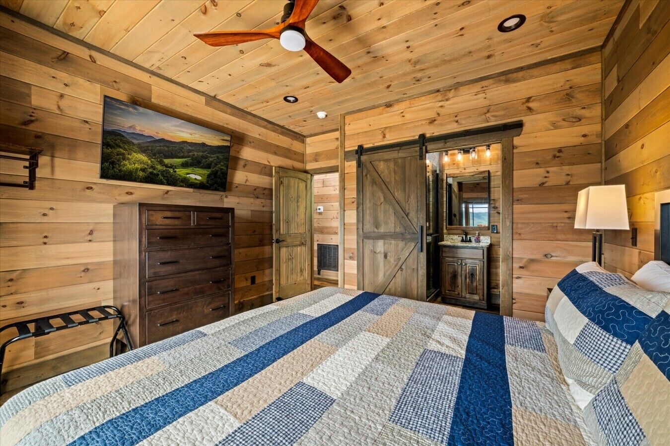 A wooden cabin interior with a bed, dresser, and a painting of a landscape.
