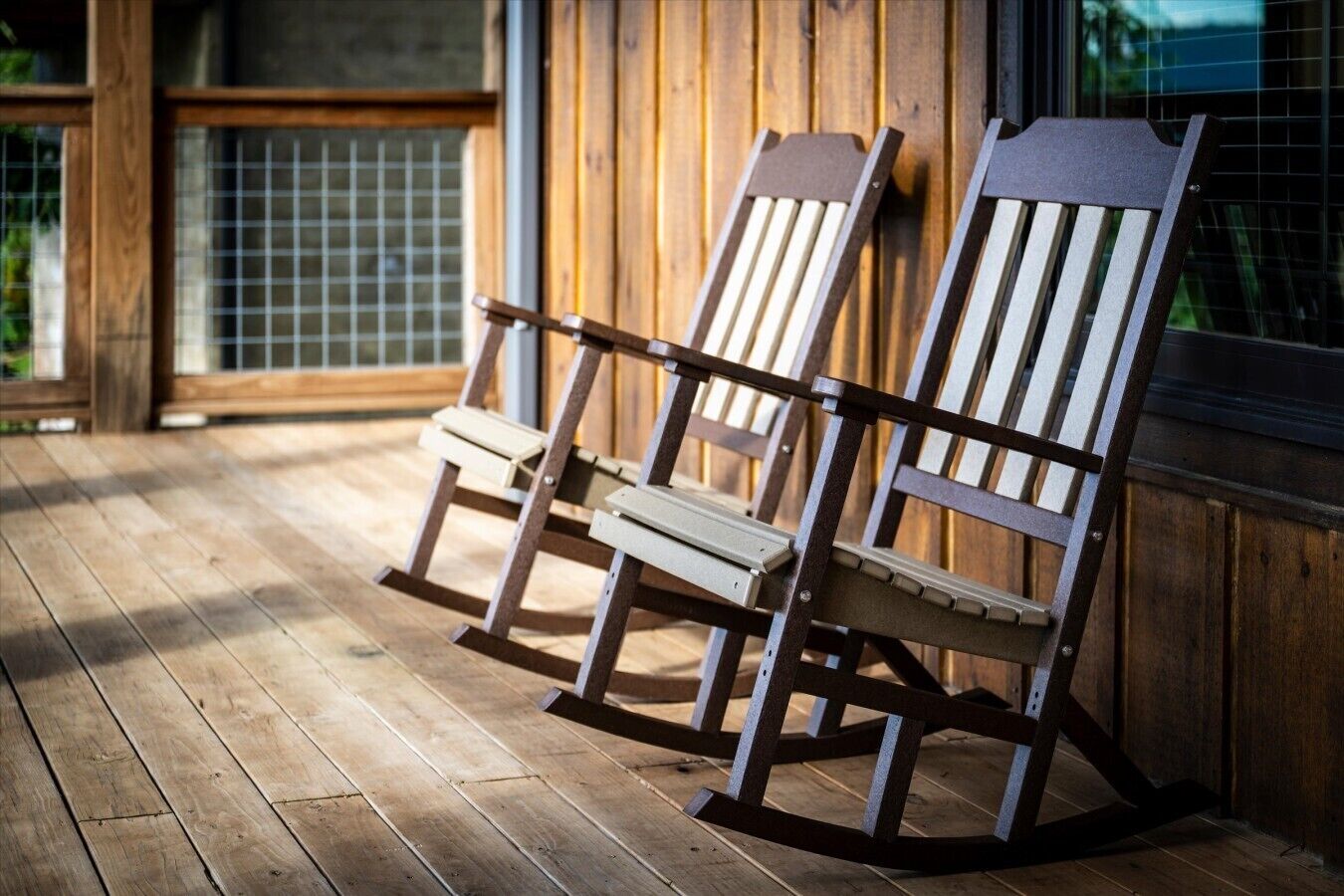 Due poltrone Adirondack su un molo di legno, con un muro e una finestra in legno sullo sfondo.