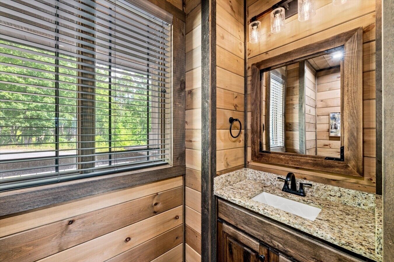 A wooden cabin bathroom with a window, a sink, and a mirror.