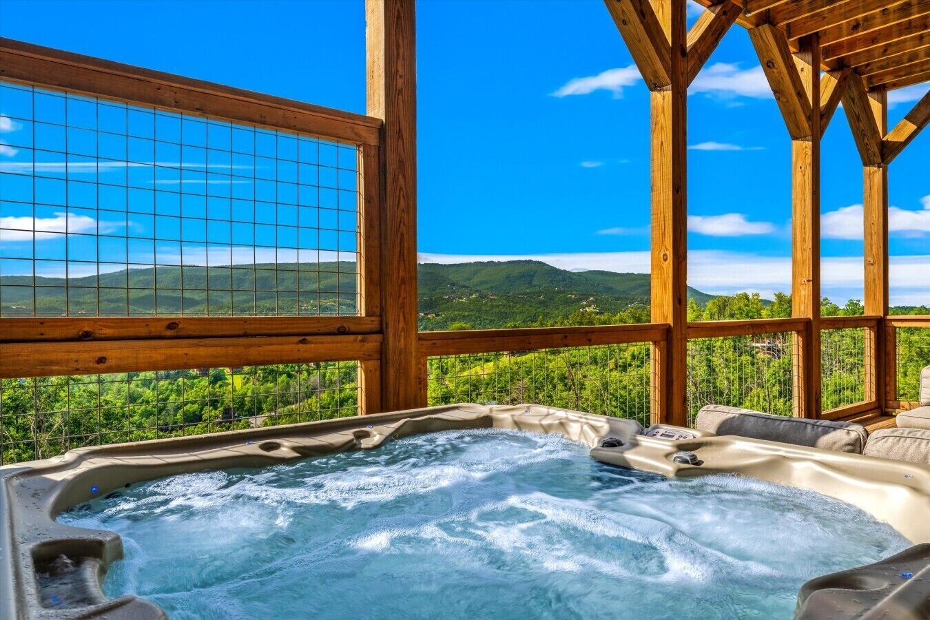 Ein Whirlpool mit einer Holzterrasse und Blick auf grüne Hügel.