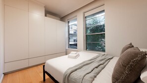 Ein Schlafzimmer mit einem Bett, einem Fenster und Einbauschränken.