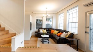 Ein modernes Wohnzimmer mit Ledersofa, Couchtisch und einer Treppe, die zu einer weiteren Ebene führt.