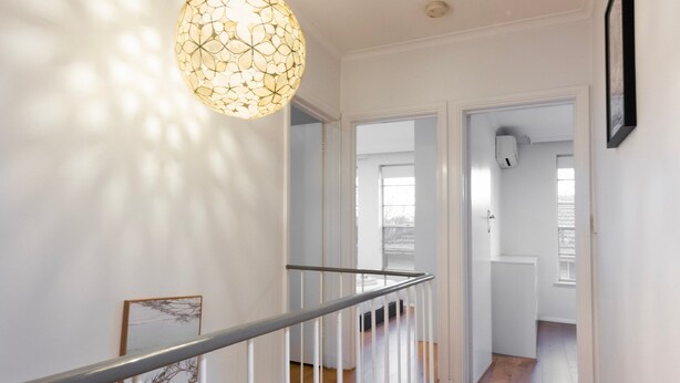En trappa med ett metallräcke som leder upp till en liten plattform. Ovanför trappan finns en väggmonterad lampa.
