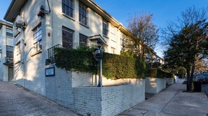 Ein zweistöckiges Wohnhaus mit Backsteinfassade, einem kleinen Garten und Blick auf die Straße.