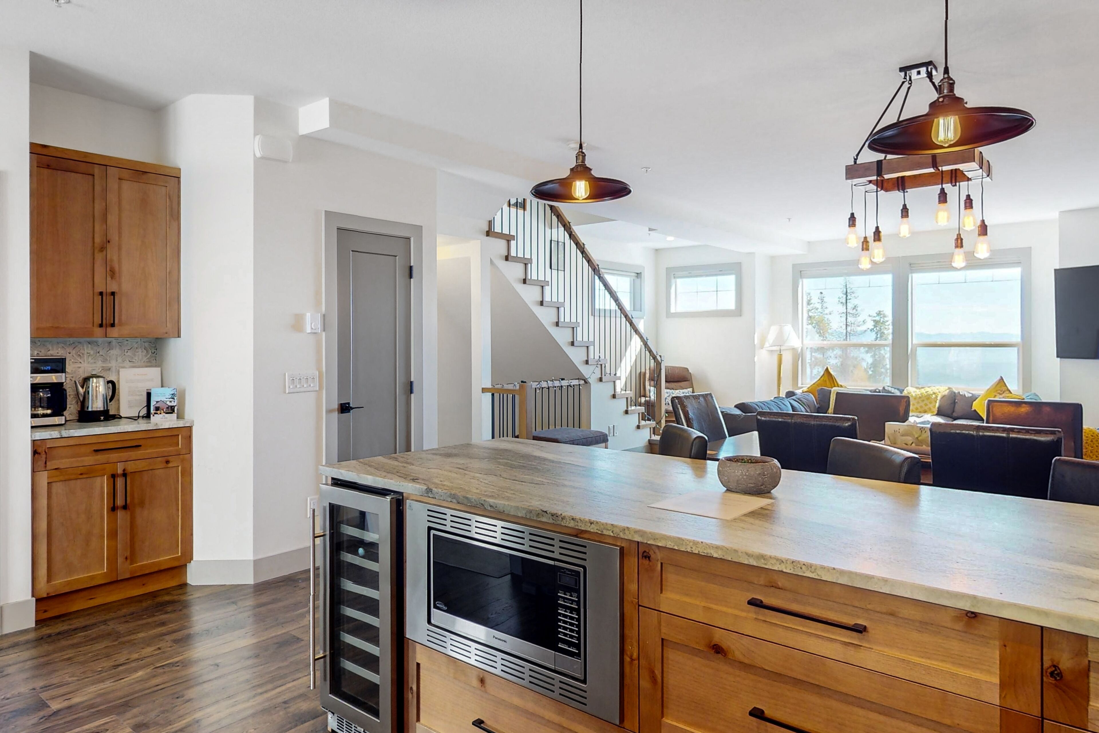 A modern kitchen with wooden cabinets, a central island, and a built-in oven.