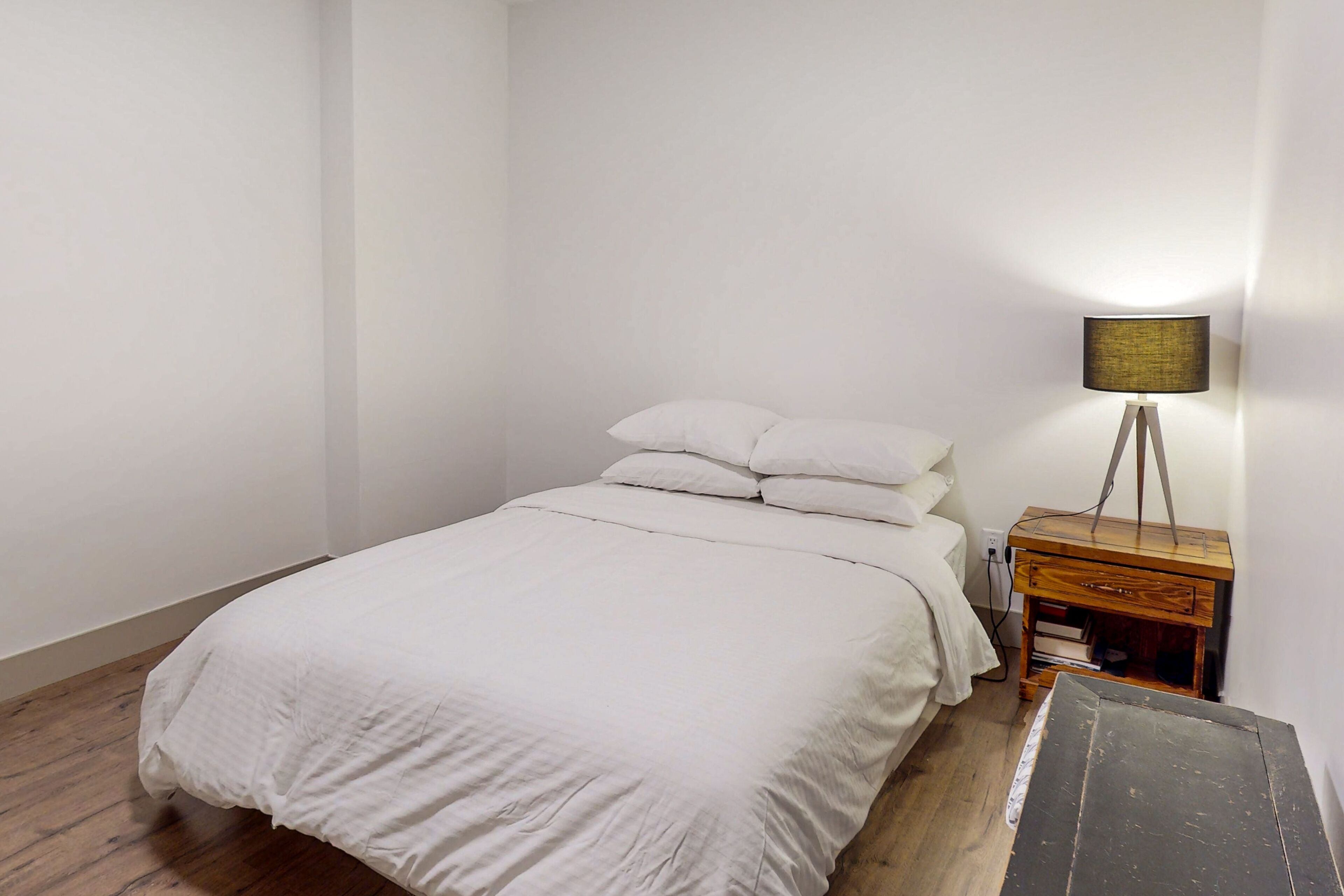 Une chambre à coucher avec un lit, une table de chevet avec une lampe et un banc en bois.