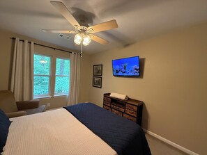 A bedroom with a bed, a ceiling fan, a TV, and a dresser. - De Soto Golf Retreat #157 (Hot Springs)