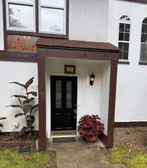 A house with a black door, a number '157' sign above it, and a porch with a potted plant. - De Soto Golf Retreat #157 (Hot Springs)