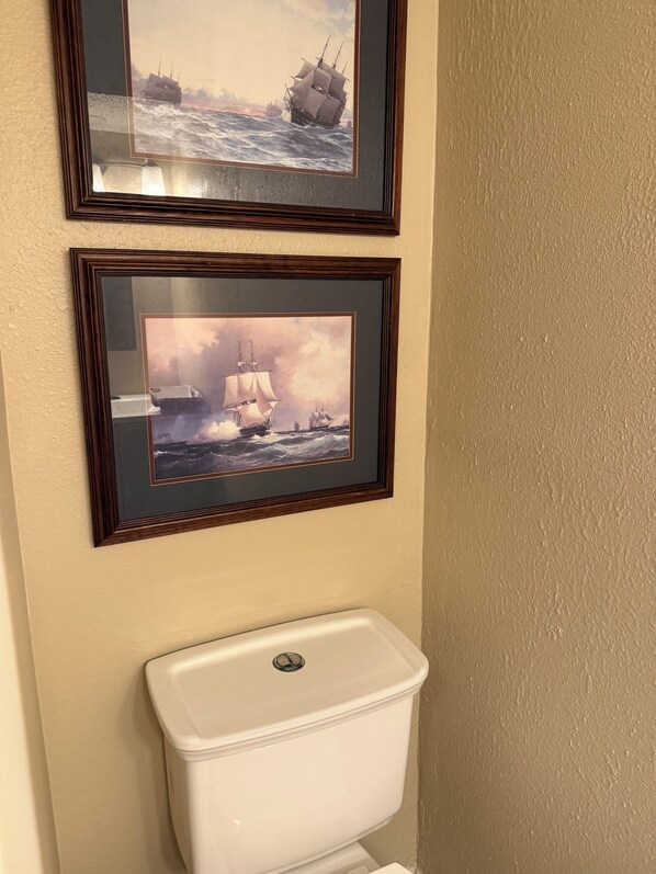Two framed maritime paintings above a toilet. - De Soto Golf Retreat #157 (Hot Springs)