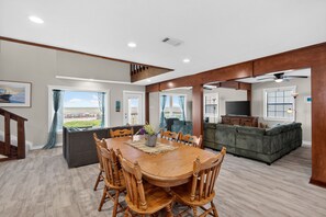 A spacious living area with a wooden dining table, chairs, a sofa, and a television. - BEACHFRONT! FIRST ROW! Stunning ocean views from two levels of decks. (Surfside Beach)
