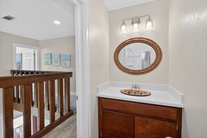 A bathroom with a wooden vanity, a round mirror, and a light fixture above the sink. - BEACHFRONT! FIRST ROW! Stunning ocean views from two levels of decks. (Surfside Beach)