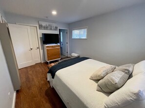 Ein Schlafzimmer mit einem Bett, einem Schminktisch, einem Fernseher und einem Fenster.