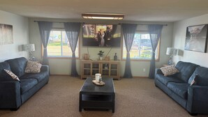Uma sala de estar com dois sofás, uma mesa de centro e uma televisão.