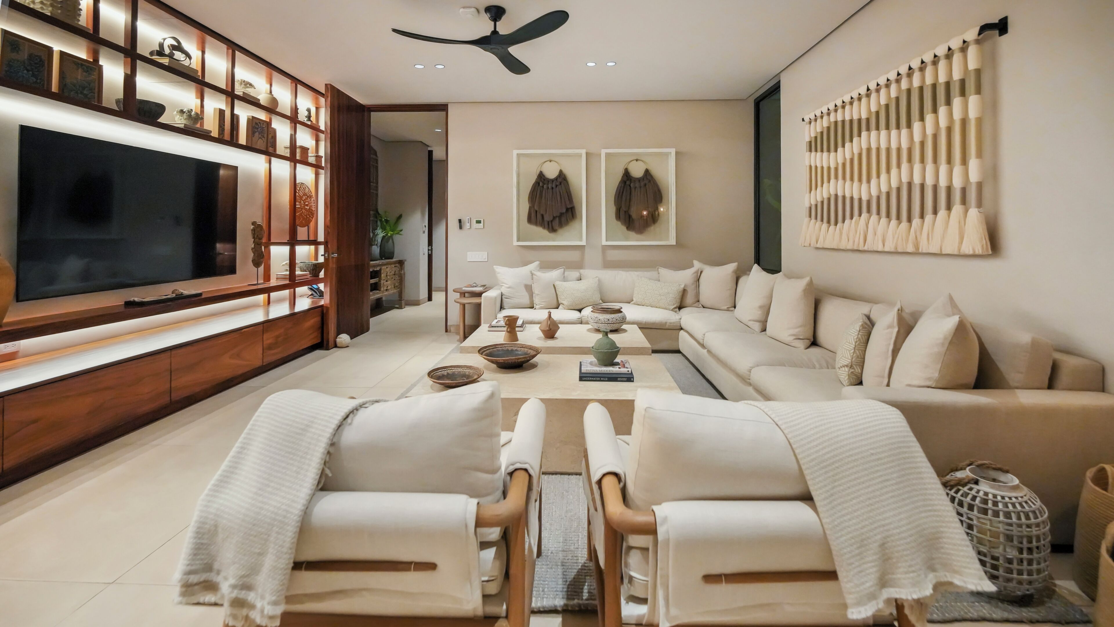 A modern living room with a flat-screen TV, a sofa set, a coffee table, and a decorative wall panel.