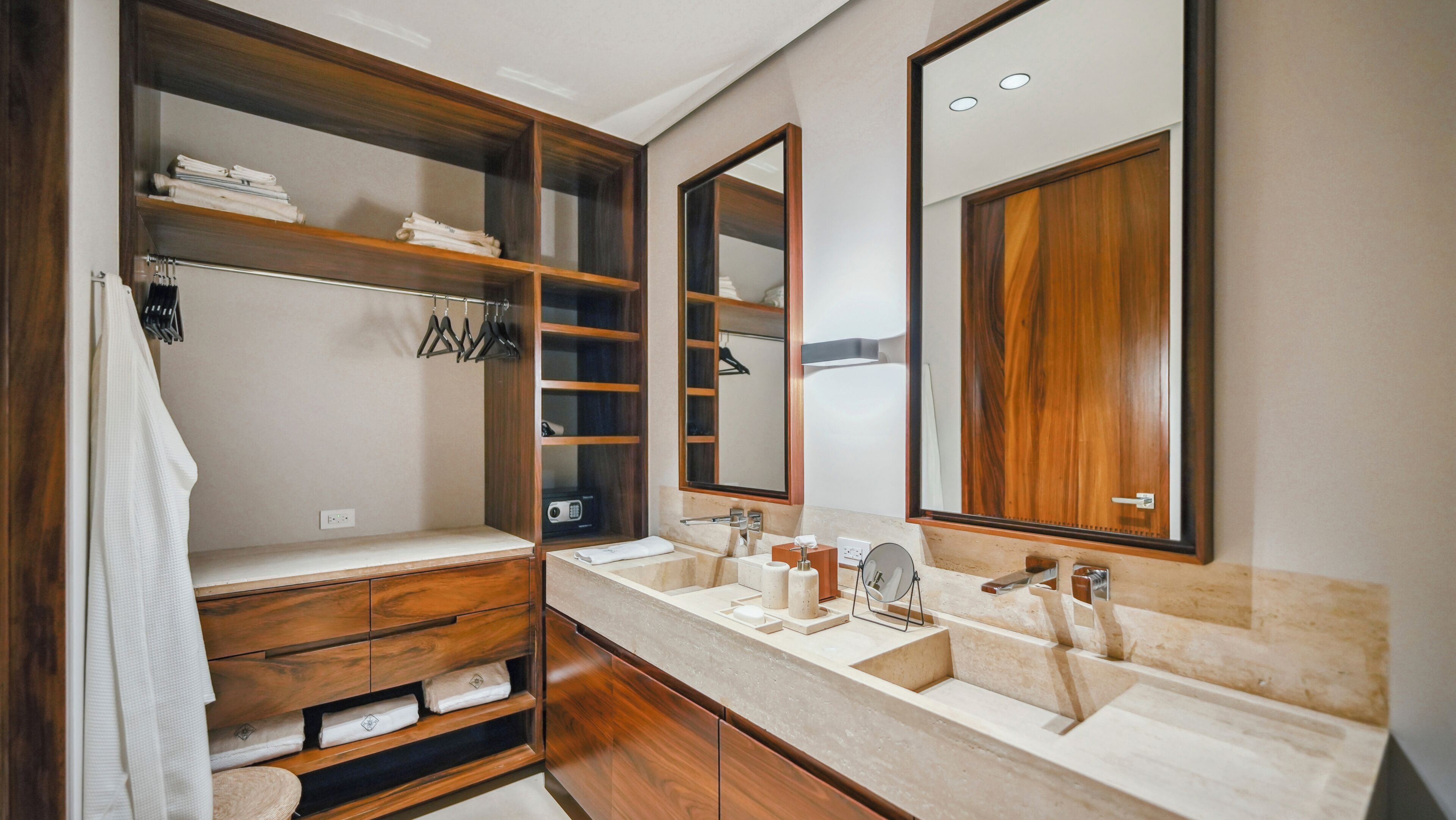 A bathroom with wooden shelves, a large mirror, two sinks, and a towel rack.