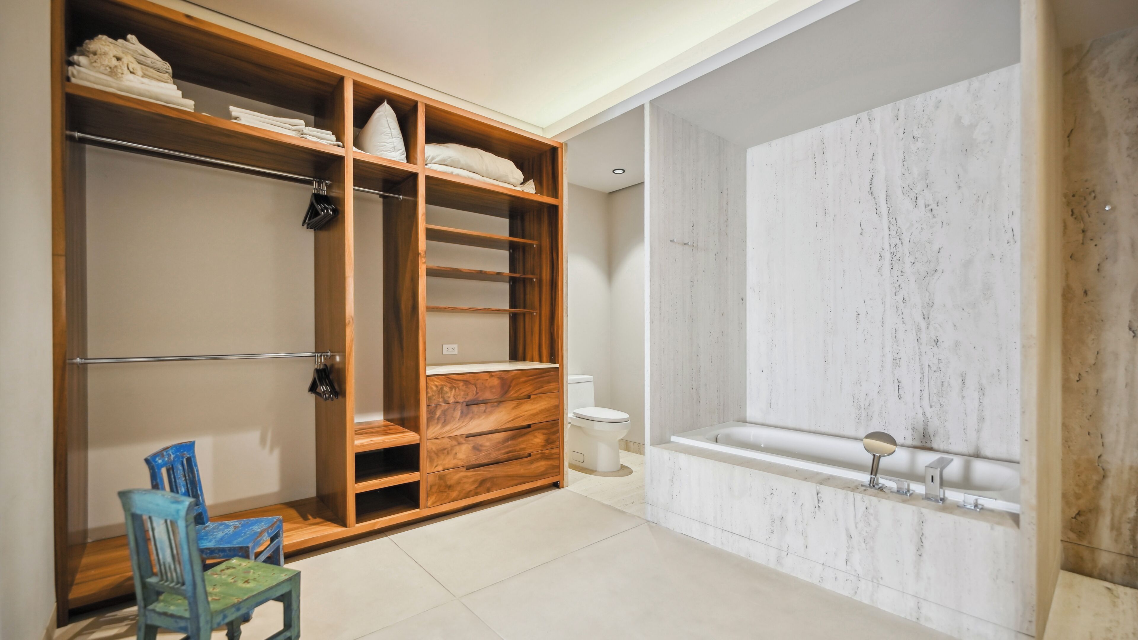 A bathroom with a bathtub, a toilet, and a wooden vanity with shelves.