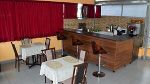A restaurant with a bar area, tables with chairs, and a kitchen in the background. - Qori Arequipa (Arequipa)