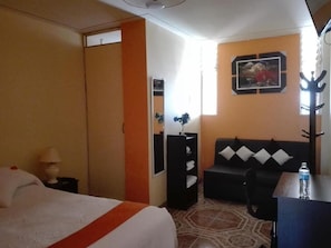Una habitación de hotel con cama, sofá, escritorio y espejo.