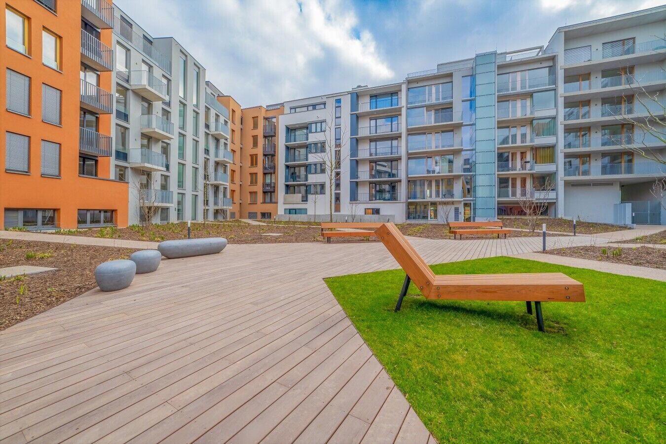 Un moderno complejo de apartamentos con asientos exteriores y un jardín ajardinado.