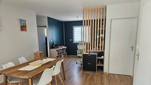 A dining area with a wooden table and chairs, a bookshelf, and a door with a vertical wooden partition. - Well-equipped house with air conditioning and a spa (Saint-Avit)