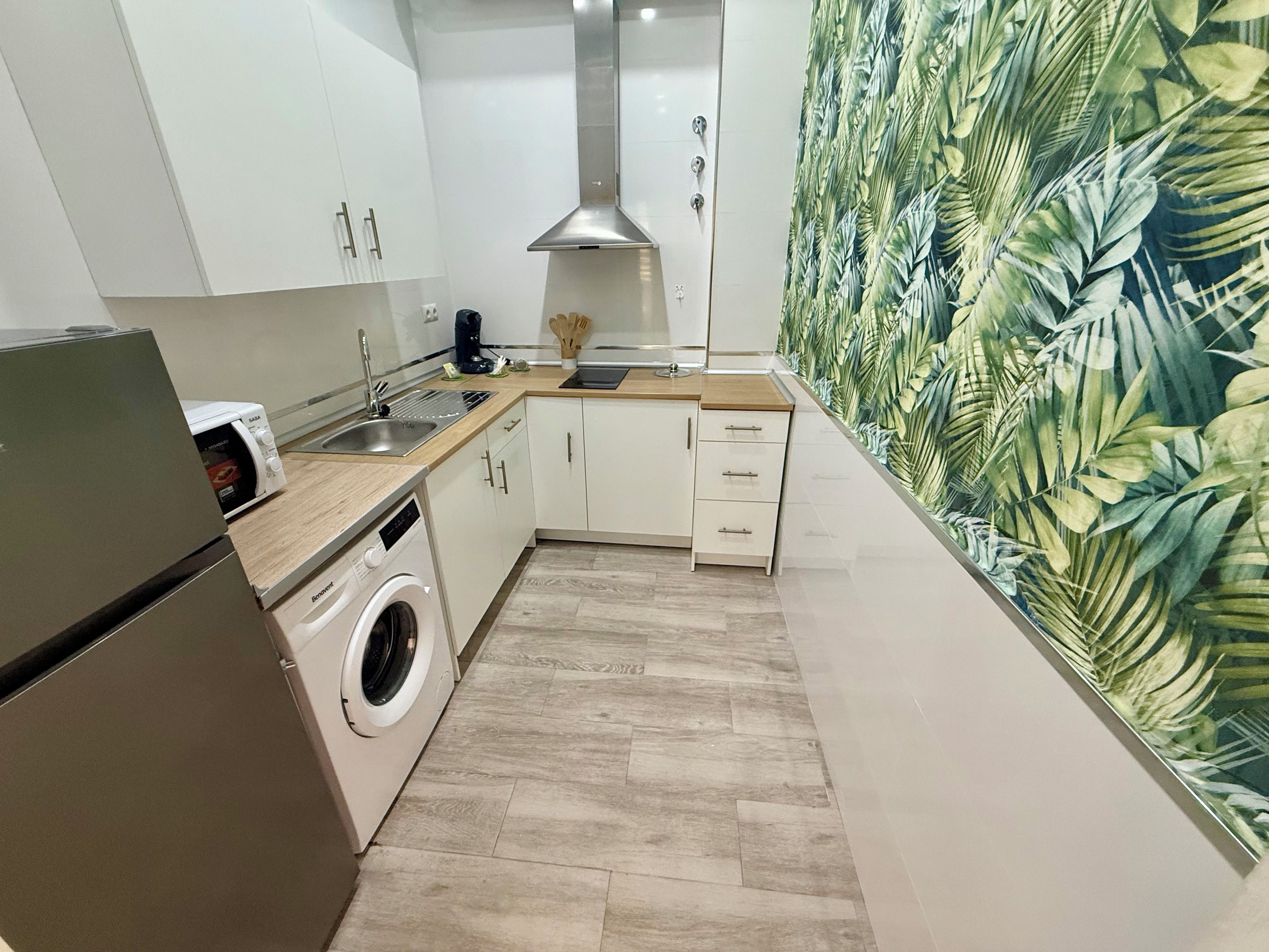 Una cocina compacta con lavadora, microondas y fregadero.