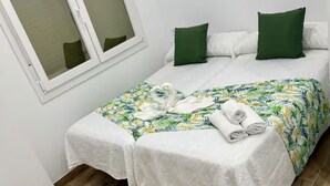 Une chambre à coucher avec un lit, deux oreillers, une fenêtre et un plancher en bois.