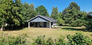 Ein Haus mit einer Veranda, einer überdachten Sitzterrasse und einem Rasen.