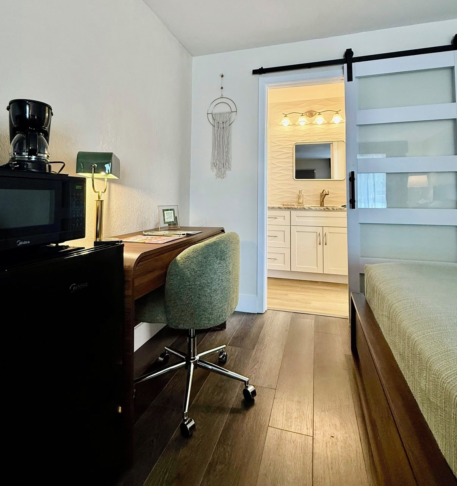 Une pièce de taille modeste, comprenant un bureau, une chaise et un lit.