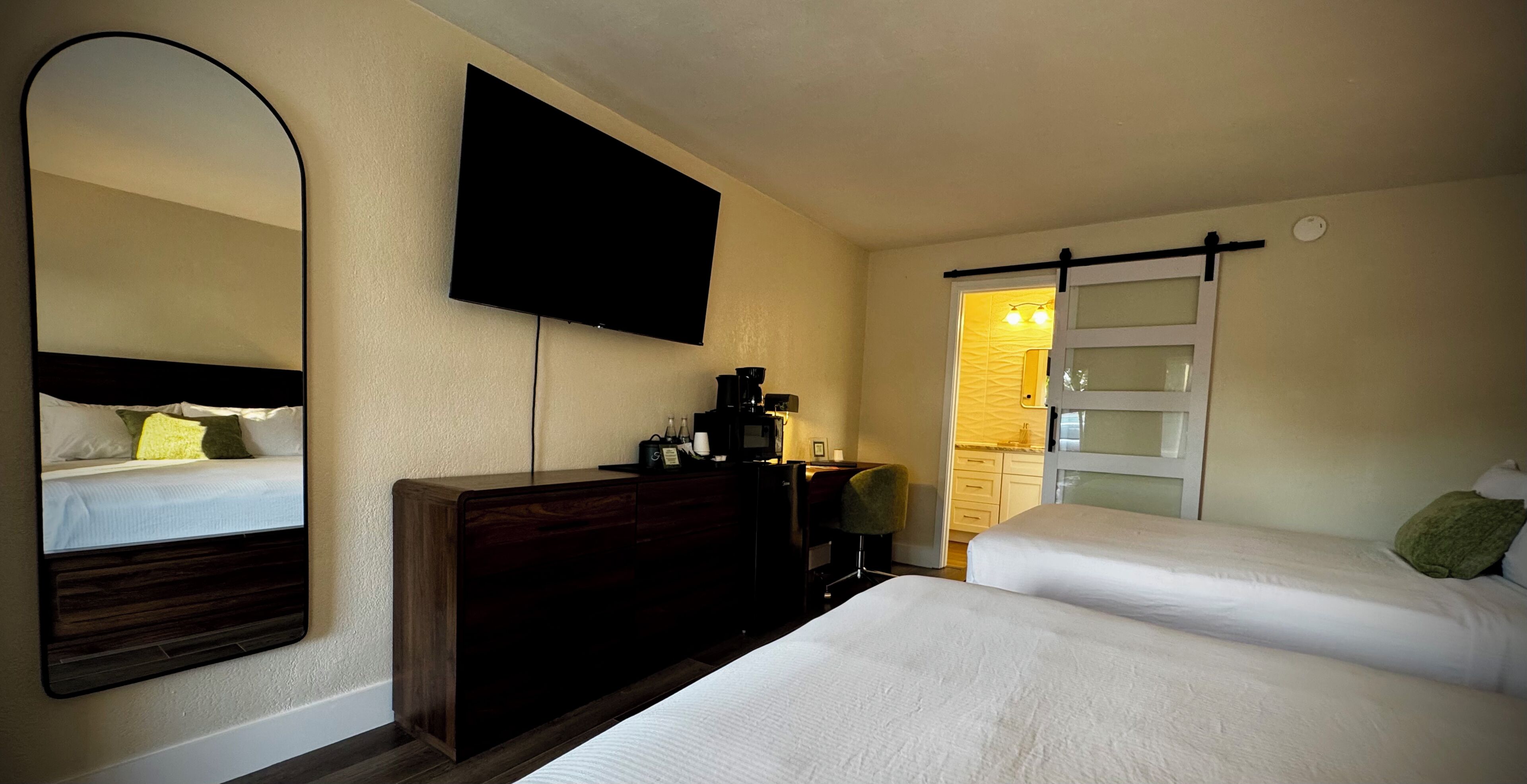 Une chambre d’hôtel avec deux lits, un téléviseur à écran plat, une commode et une salle de bain avec un rideau de douche.
