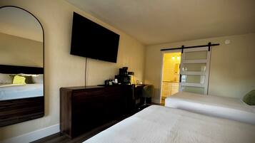 Une chambre d’hôtel avec deux lits, un téléviseur à écran plat, une commode et une salle de bain avec un rideau de douche.