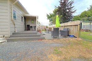 A house with a gravel driveway, outdoor seating area with chairs and a table, and a wooden fence.