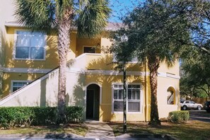 A yellow two-story house with a front entrance, a covered porch, and a driveway. - Bright and Spacious 1Bed/1Bath condo. (Clearwater)