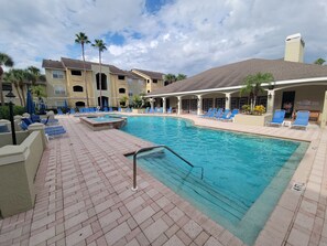 A swimming pool with blue lounge chairs and a brick patio. - Bright and Spacious 1Bed/1Bath condo. (Clearwater)