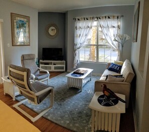 Ett vardagsrum med en tv, en soffa, en fåtölj och ett soffbord.