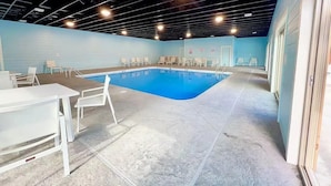 An indoor swimming pool with a blue floor, surrounded by white chairs and tables. - Luxe 4BR-4BA, Branson Retreat with Lake Views, Pools + Pickleball (Branson)