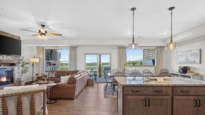 A spacious living area with a fireplace, a dining area, and a kitchen with a large island. - Luxe 4BR-4BA, Branson Retreat with Lake Views, Pools + Pickleball (Branson)
